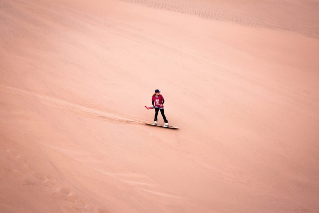 a man riding a snowboard down a sandy hill