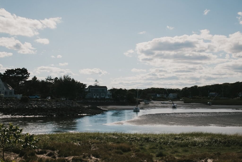 body of water near trees and buildings under white clouds and blue sky during daytime