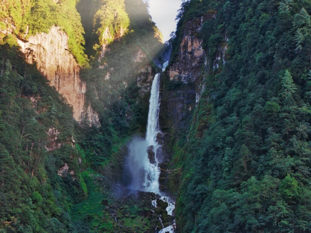Tall waterfall cascading down a lush green mountainside.