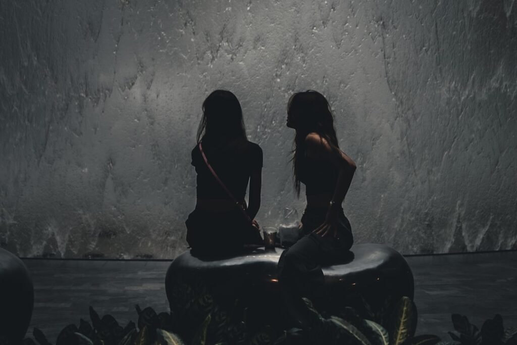 two women sitting on stools in front of a fountain